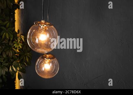 Decorative light tungsten bulbs against black wall background Stock Photo