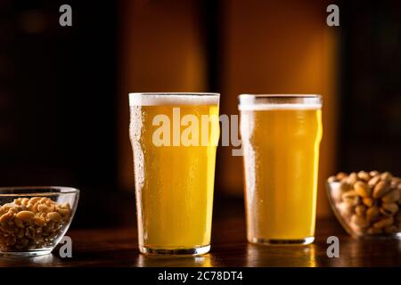 Beer set in pub. Two glasses of ale, nuts and pistachios on table in interior Stock Photo