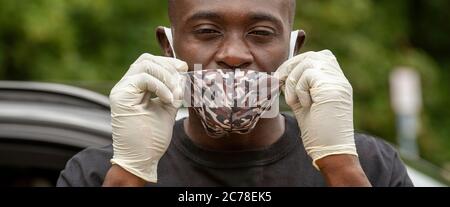 Hampshire, England, UK. 2020. A black male wearing a face mask with camouflage design and protective rubber gloves during the Covid-19 outbreak, Stock Photo