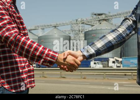 Businessmen shake hands against silos. Agriculture business Stock Photo