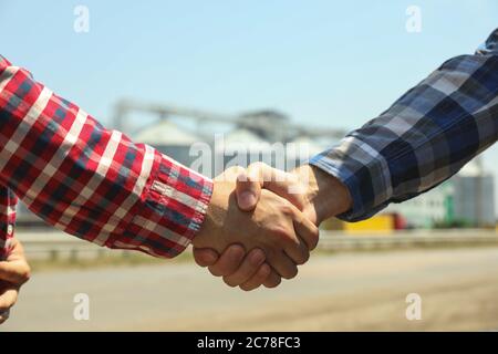 Businessmen shake hands against silos. Agriculture business Stock Photo