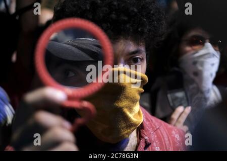 A protestor holds a mirror up to a police officer as thousands of demonstrators gather in front of the Official Residence Prime Minister Benjamin Netanyahu on Balfour street to protest against his corruption and continued governance. Jerusalem Israel