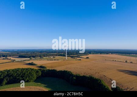 Grabow, Germany. 11th July, 2020. A windmill turns on a field. Behind it there is a 324 meter and a 210 meter high transmitter mast. They belong to Sender Burg. During the Cold War, the German Soldiers' Transmitter and the Freedom Transmitter 904 were broadcast from there. (aerial photo with drone) Credit: Stephan Schulz/dpa-Zentralbild/ZB/dpa/Alamy Live News Stock Photo