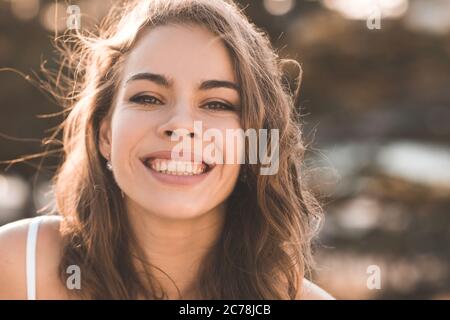 Smiling adult woman 30-35 year old with healthy skin with wrinkles posing outdoors closeup. Summer season. 20s. Stock Photo