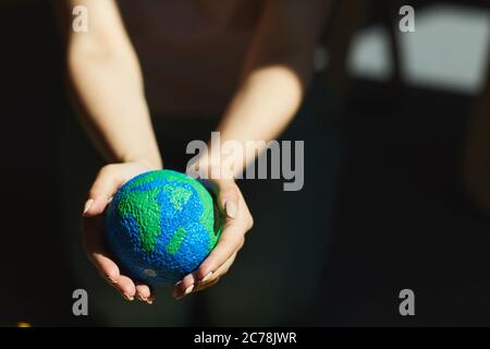 Close-up of unrecognizable woman holding planet model in hands in sunlight, saving Earth concept Stock Photo