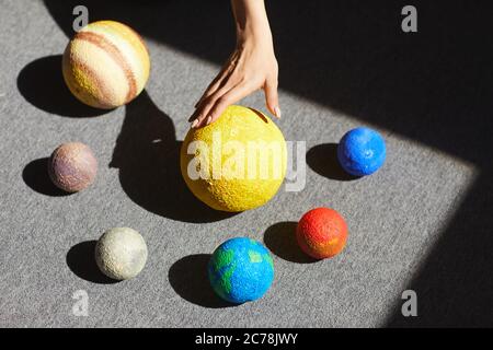 Above view of unrecognizable woman placing planet models according to solar system in light on floor Stock Photo