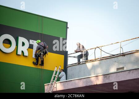 BELGRADE, SERBIA - OCTOBER 8, 2018: Three men, construction workers, wearing security equipment, fixing and renovating a building on a rooftop of an i Stock Photo