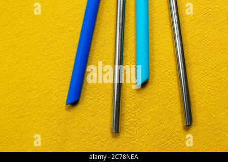 Group of both metal and silicone reusable straws on a yellow background Stock Photo