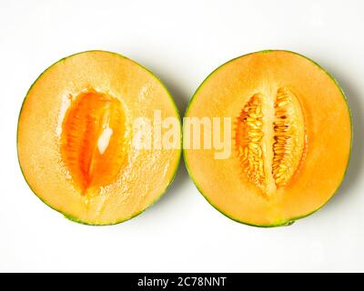 Two halves of a canteloupe melon one with seeds and one without isolated on a white background Stock Photo