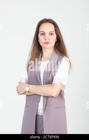 beautiful young woman in business strict clothes poses against a white wall