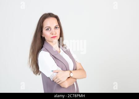 beautiful young woman in business strict clothes poses against a white wall