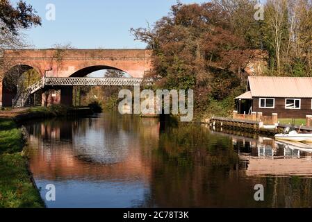 A red brick railway bridge and a footbridge reflected in the still waters of the River Wey navigation in Guildford, Surrey, United Kingdom in autumn Stock Photo