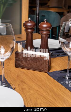Salt and pepper dishes and napkin on a wooden table. A table in a restaurant. Stock Photo