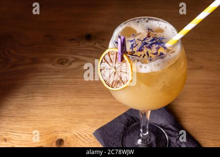 Alcoholic cocktail in a large glass with a slice of orange and a tube on a wooden table on a black background. Drink with champagne and vodka. Stock Photo