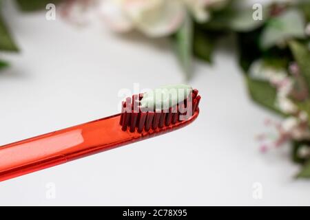 Red toothbrush with green natural toothpaste on a white background. Stock Photo