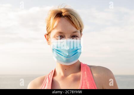 portrait of a beautiful blonde woman with a protective mask with the sky in the background, concept of prevention and health care Stock Photo