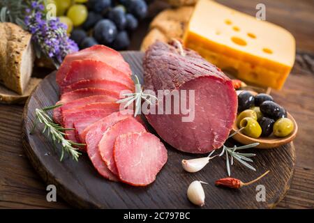 Smoked pork meat on the cutting board with cheese,bread and olives Stock Photo