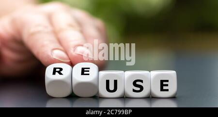 Hand turns dice and changes the word use to reuse. Stock Photo