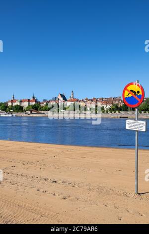 No swimming warning sign because of dangerous current on a beach at Vistula River in city of Warsaw in Poland, Old Town skyline in the background. Stock Photo