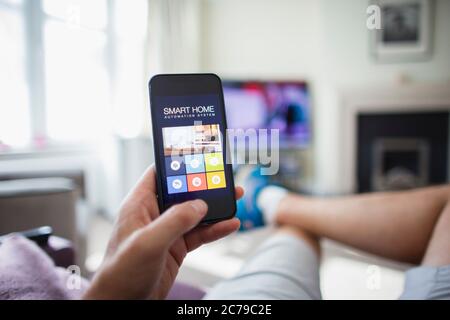 POV man checking home automation on smart phone in living room Stock Photo
