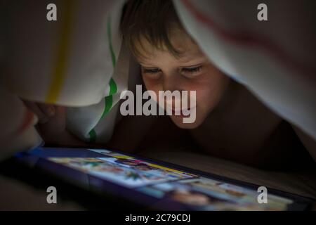 Close up boy using digital tablet under blanket Stock Photo