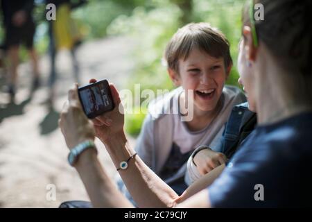 Happy mother and sons video chatting with friends on smart phone Stock Photo