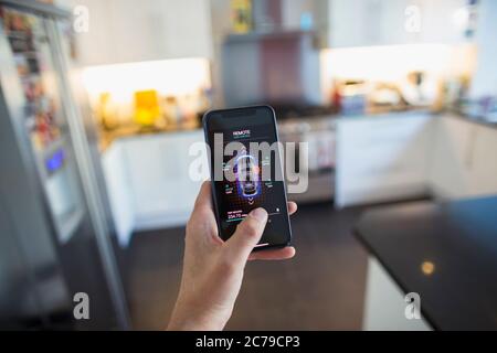 POV Man securing car alarm from smart phone screen in kitchen Stock Photo