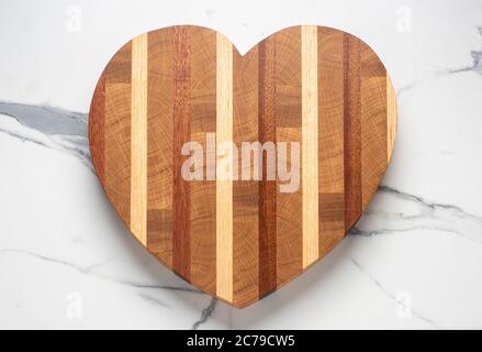 Heart shaped wooden chopping board on marble surface Stock Photo