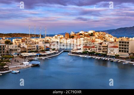 Colorful view of Voulismeni lake and Agios Nikolaos town on Crete island, Greece at sunset with beautiful clouds on blue sky Stock Photo