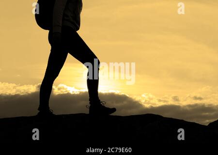 Hiker's Legs on the Rocky Trail at Summer Sunset. Travel and Adventure Concept. Stock Photo