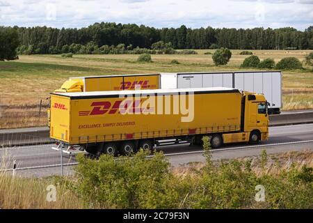 Trucks in traffic on the E4 motorway. DHL (Dalsey, Hillblom and Lynn) International GmbH is a United States-founded German courier, parcel, and express mail service which is a division of the German logistics company Deutsche Post DHL. Photo Jeppe Gustafsson Stock Photo