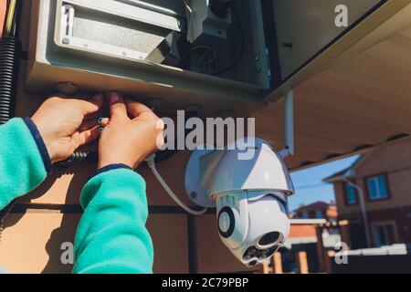 technician female setup cctv camera on wall. Stock Photo