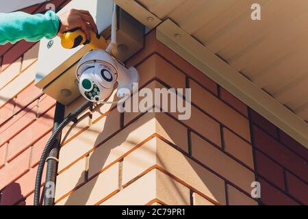 technician female setup cctv camera on wall. Stock Photo