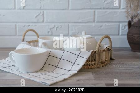 White ceramic Tea pot and cups on rattan tray on wooden table Stock Photo