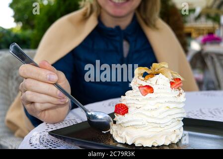 Smiling woman eat Beautiful pavlova cakes with strawberries and spoon in restaurant. Stock Photo