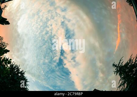 Dramatic fish eye view of textured and colorful clouds in the sky during sunset Stock Photo