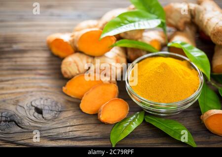 Turmeric powder and turmeric roots on the wooden table Stock Photo