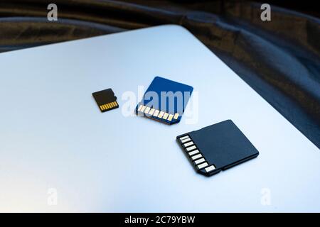 blue and black SD memory cards on silver laptop surface, close-up. concept of memory, information storage, data storage Stock Photo