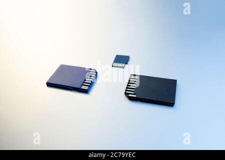 Three micro SD memory cards on gray background. Memory cards for digital files, close up. Flash drives lie on a gray surface Stock Photo