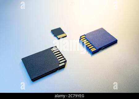 three SD Cards or memory cards for digital cameras and devices and on a gray metal surface Stock Photo