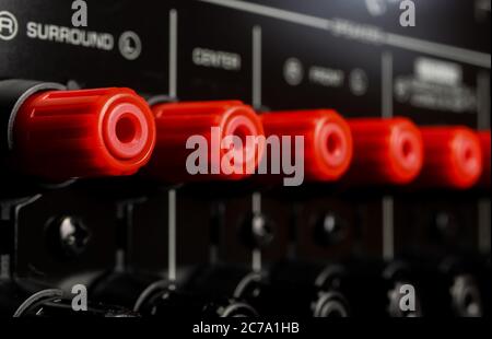 View on isolated red speaker outputs in a row of back side of black dolby surround home cinema receiver Stock Photo