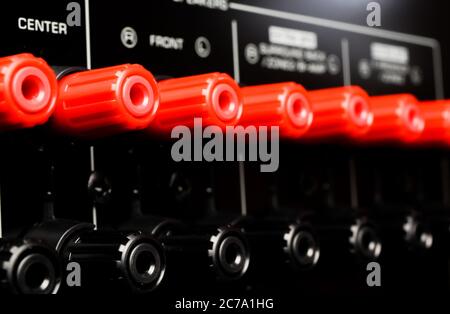 View on isolated red speaker outputs in a row of back side of black dolby surround home cinema receiver Stock Photo