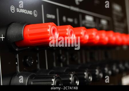 View on isolated red speaker outputs in a row of back side of black dolby surround home cinema receiver Stock Photo