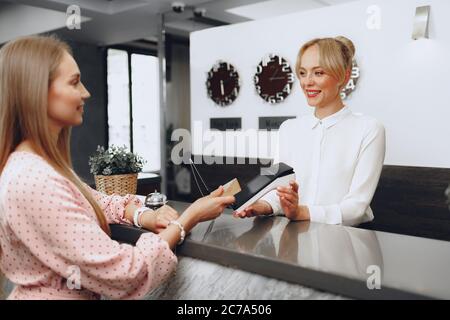 Young beautiful woman hotel guest paying for her stay with credit card at front desk Stock Photo