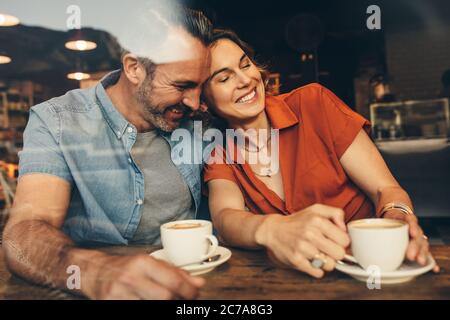 Happy couple sitting together at a coffee shop and relaxing. Couple in love meeting at a cafe with coffee on table. Stock Photo