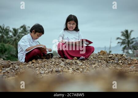 Two elementary school students studying together at public park Stock Photo