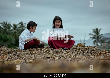 Two elementary school students studying together at public park Stock Photo
