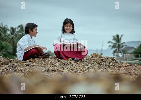 Two elementary school students studying together at public park Stock Photo