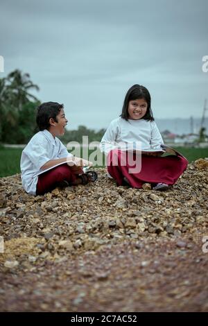Two elementary school students studying together at public park Stock Photo