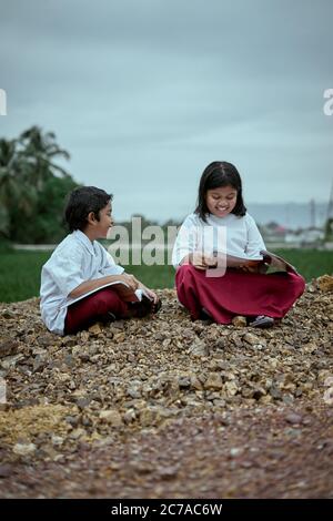 Two elementary school students studying together at public park Stock Photo